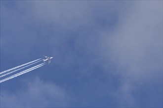 Airbus A380 aircraft in flight amongst white clouds with a contrail or vapour trail behind,