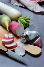 Various radishes on a wooden board, cut up and sliced