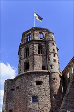 Tower of a castle (Heidelberg Castle), with round windows and a flag on a blue sky, Heidelberg,