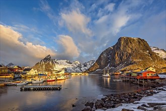 Morning light shines on a snowy fishing village in Lofoten with boats docked at the harbor, Lofoten