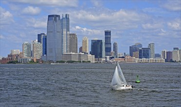 Sailboat on Hudson River in front of skyscraper skyline of Jersey City, New Jersey, USA, North