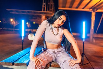 Portrait of a trap dancer sitting confident in an urban park looking at camera at night