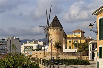 Traditional windmill with old buildings under a blue sky with scattered clouds, Palma De Mallorca