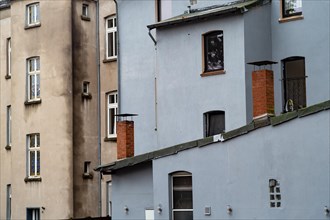 Worn facade of a multi-storey residential building with different windows