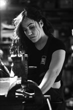 Hispanic latino long haired brunette sexy woman mechanic examining a car part in a well-equipped