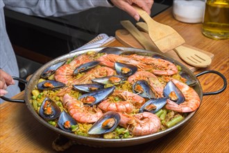 A traditional Spanish paella with shrimp and mussels in a rustic kitchen setup, typical Spanish