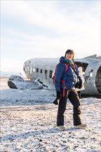 Portrait of adventurous photographer woman in winter in Iceland on the plane by Solheimasandur