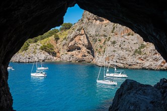 Sailing boats, yachts are anchored in front of the Torrent de Pareis gorge, turquoise-blue, calm