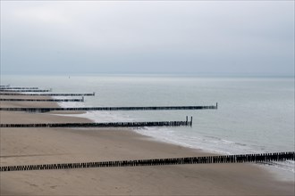 Empty breakwaters jut into the calm sea on a cloudy day
