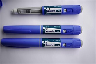 Three blue insulin pens for diabetics on a white surface, dosage of Ozempic 1mg, for diabetes 2