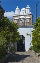 A white church and three domes rise between trees, Byzantine fortress, nunnery, monastery, Koroni,