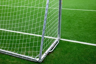 Part of a football goal on artificial turf with clearly visible white lines