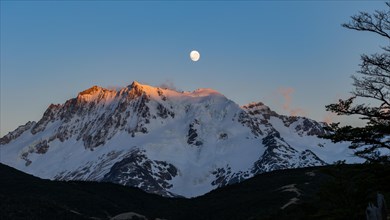 The snow-covered summit of Cerro Hermoso at sunrise with the moon, Perito Moreno National Park,