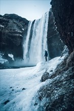 Silhouette of woman in winter in Iceland under the Skogafoss waterfall with temperatures of 20
