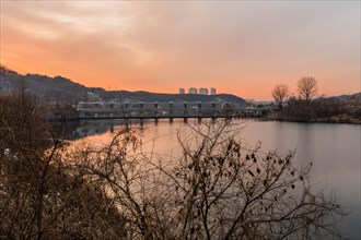 Twilight falls over a river with a dam, under a gradient sunset sky, in South Korea