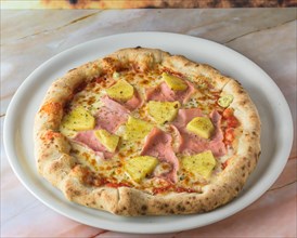 Tropical Hawaiian pizza with pineapple slices and ham on a baked dough base served whole with