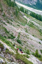 Hikers on an alpine path on the mountainside in the Dolomites mountains, Val Gardena, Italy, Europe