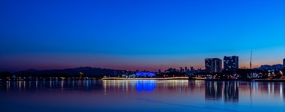 Tranquil city waterfront under the hues of dusk, with lights reflecting on water, in South Korea