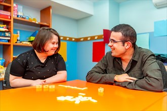 Woman with down syndrome and disabled man playing board games in a day center
