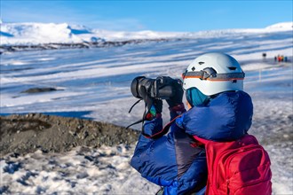 Adventurous female photographer in winter in Iceland photographing at the Vatnajokull Glacier