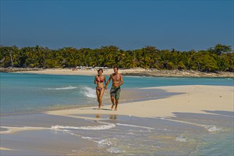 Couple walking on a white sand beach on the island of Nosy Iranja near Nosy Be, Madagascar, Africa