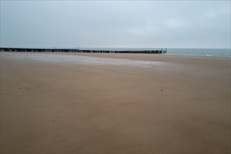 Deserted stretch of beach with breakwaters on an overcast day, Westkapelle, Zeeland, Netherlands
