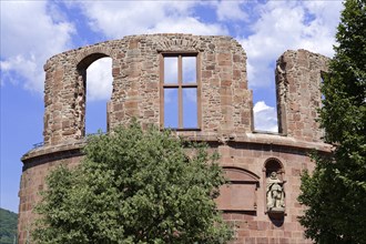 Old ruined wall (Heidelberg Castle), with window opening, sculpture and tree in front of it,
