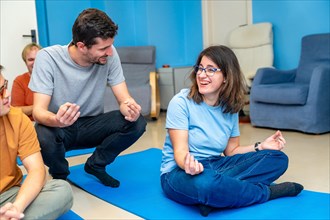 Yoga instructor teaching the lotus position to a disabled woman sitting on a mat in a yoga group