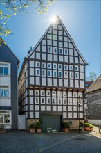 Large, impressive half-timbered house under a bright blue sky with rays of sunshine, Old Town,