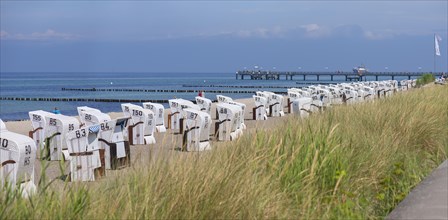 White beach chairs on the beach, behind the pier in Kuehlungsborn, Mecklenburg-Vorpommern, Germany,