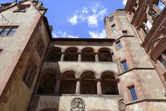 Part of a castle (Heidelberg Castle), with rows of arches made of red sandstone under a clear sky,