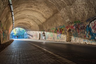 A cyclist rides through a graffiti tunnel with focussed lighting, Nordbahntrasse, Elberfeld,