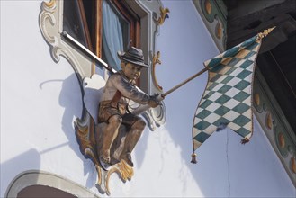 Wooden figure of a boy in lederhosen with Bavarian diamond flag white-blue at the Fraundorfer Inn,