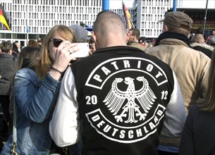 A participant in the Merkel muss weg demonstration wears a jacket labelled Patriot . Demonstration