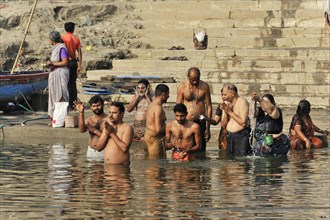 A group of people performing traditional rituals in a river, Varanasi, Uttar Pradesh, India, Asia