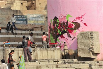 Vibrant graffiti art on a wall next to people in an Indian city, Varanasi, Uttar Pradesh, India,