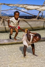 Kids playing on a little sailing boat, Nosy Iranja near Nosy Be, Madagascar, Africa