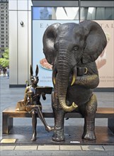 Bronze artwork for endangered animals, elephant and rabbit sitting on bench drinking coffee,