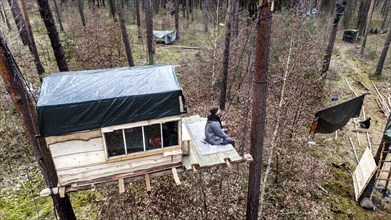 A climate activist sits in a tree house in the Gruenheide forest. The activist group Stop Tesla has