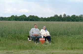 A couple of pensioners sitting on folding chairs at the edge of a field, 10 June 1997
