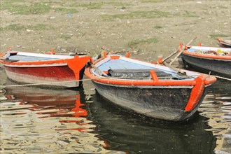 Several small boats on calm waters with reflections in the water, Varanasi, Uttar Pradesh, India,