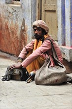Thoughtful man in traditional dress sitting on a busy street, Varanasi, Uttar Pradesh, India, Asia