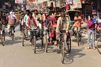 Busy street scene with many cycle rickshaws and passers-by, Varanasi, Uttar Pradesh, India, Asia