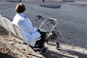 A pensioner sits on a bench, in front of her is a rollator, Bad Harzburg, 06.10.2018