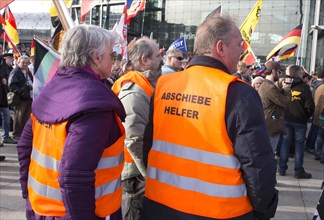 Participants in the Merkel muss weg demonstration wearing waistcoats with the words Abschiebehelfer