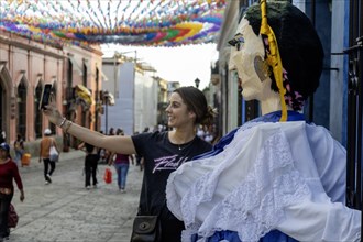 Oaxaca, Mexico, A tourist takes a selfie with a giant papier mache puppet on the Alcala, a