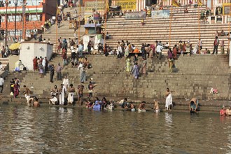 People on the steps of a river bank in a city, buildings in the background, Varanasi, Uttar