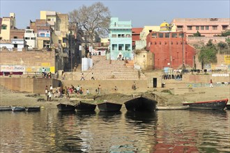 View of a river landscape with banks, boats and city skyline in the background, Varanasi, Uttar
