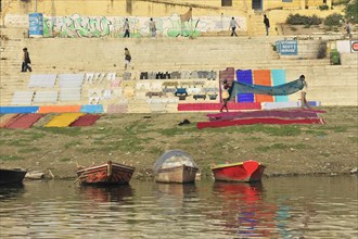 Colourful laundry drying next to a river bank with graffiti in the background, Varanasi, Uttar