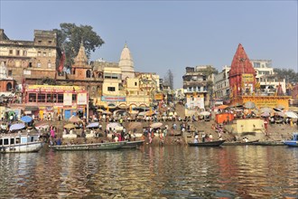 Lively activities at the ghats with a view of boats and temples along a river, Varanasi, Uttar